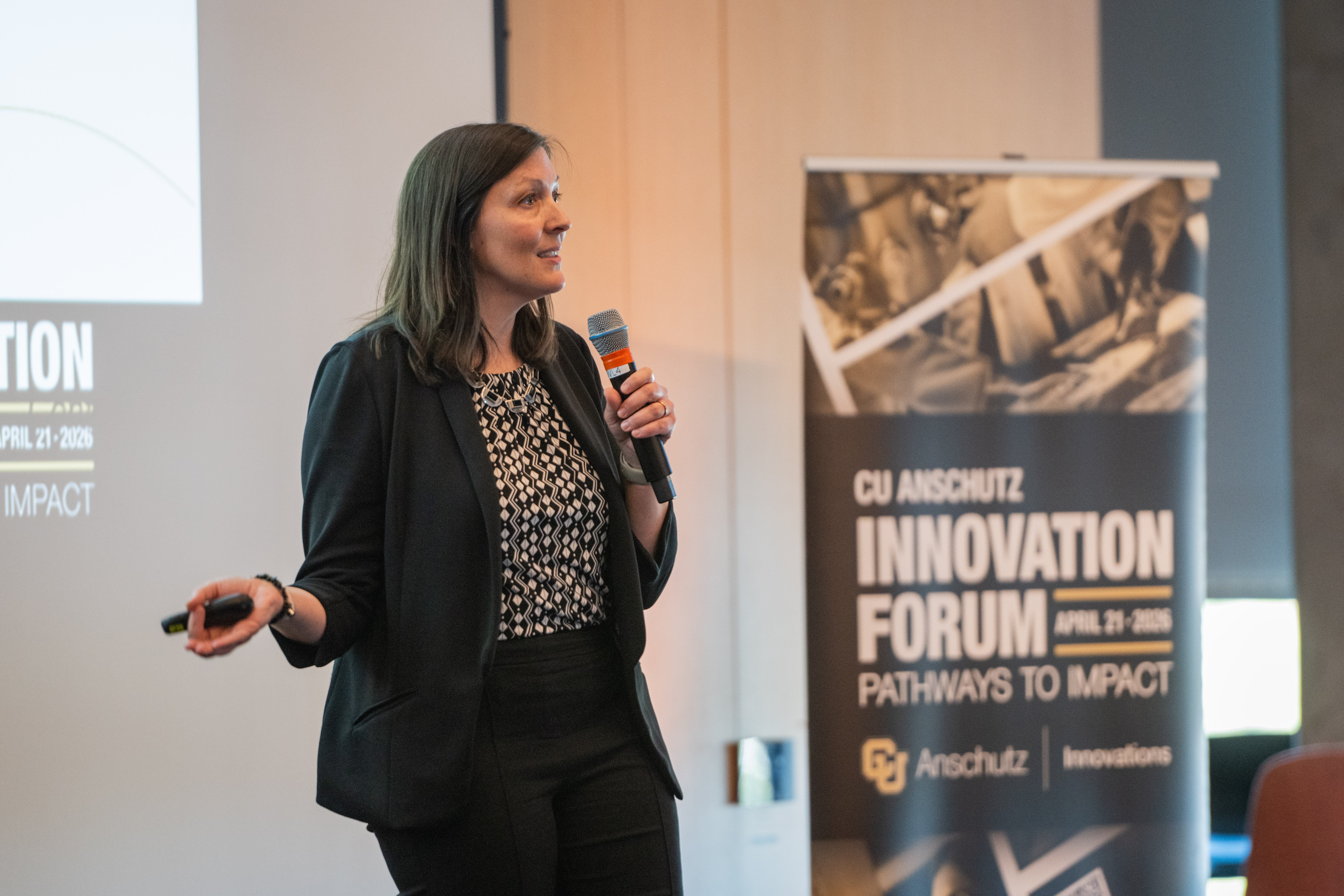Allison Dempsey stands, mic in hand, on stage presenting mindLAMP Care. A banner is to her right with the words "CU Anschutz Innovation Forum, April 21, 2026, Pathways to Impact, with the CU Anschutz Innovations lockup at the bottom.