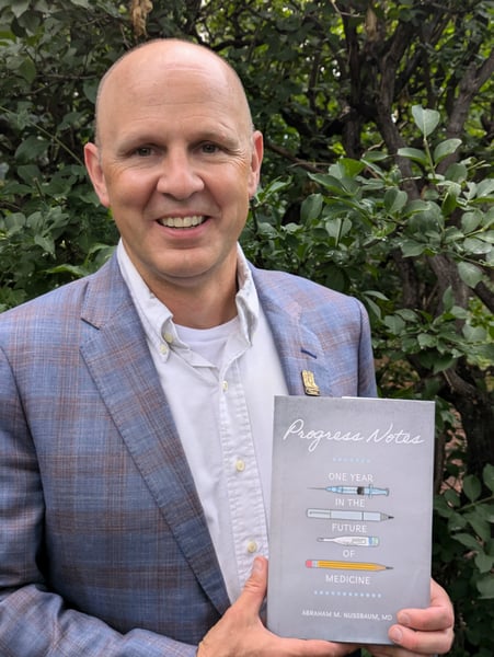 Abraham Nussbaum, MD, holding his new book, "Progress Notes."