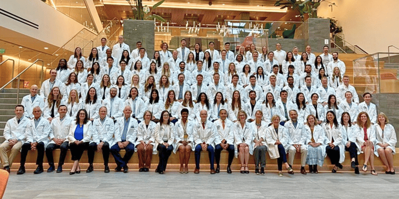 Image of a large group of doctors sitting together while wearing their white coats.