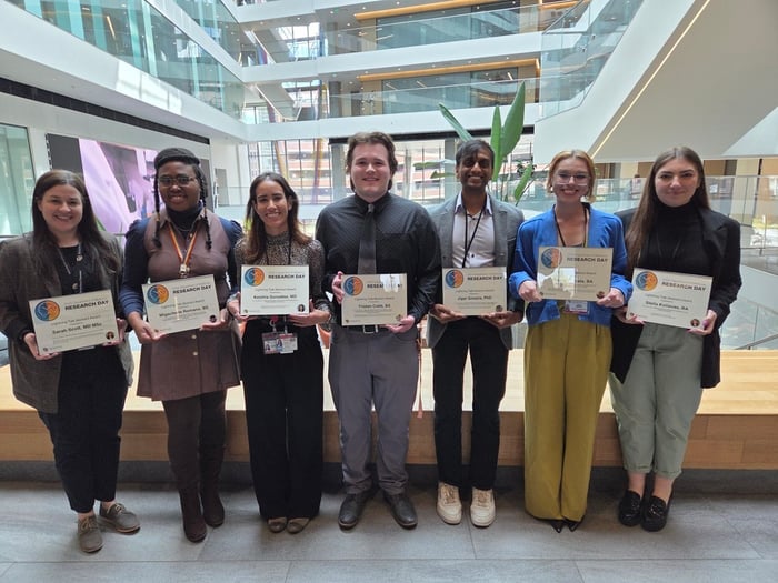 Seven adults hold up certificates.