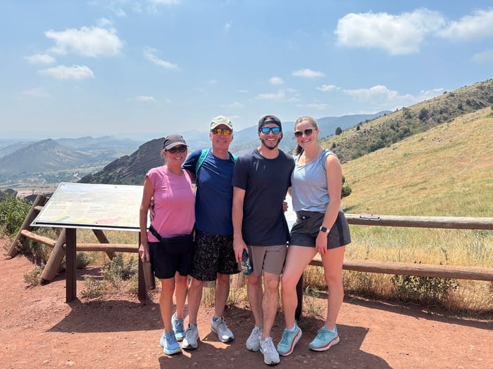 A group of four people smiling on a trail outdoors.