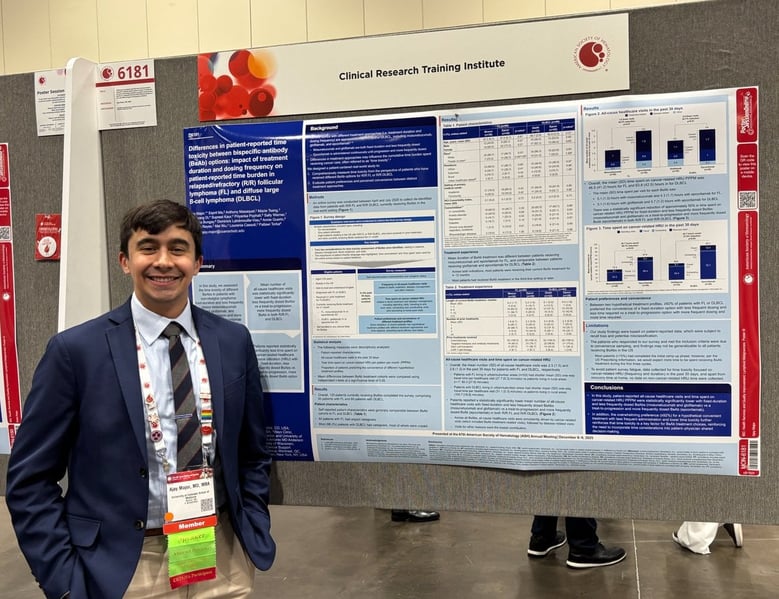 Ajay Major, MD, MBA, smiles while standing beside a poster board of his research.