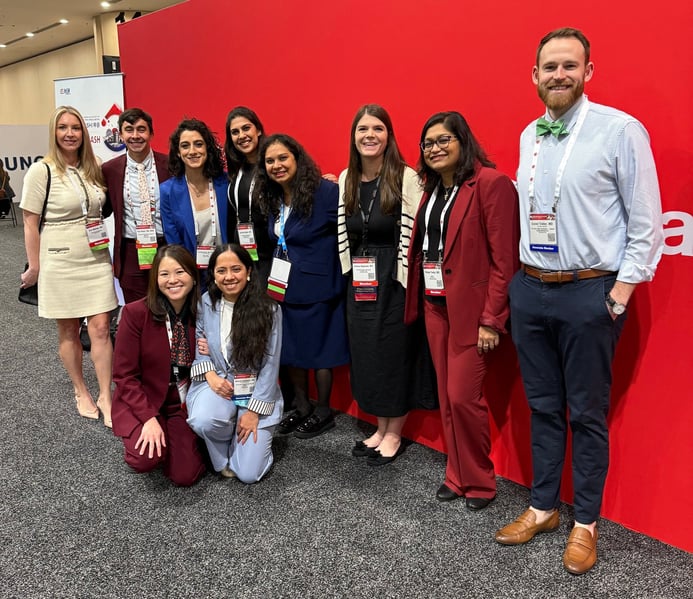 A group of 10 people smile for a photo while at a medical conference.