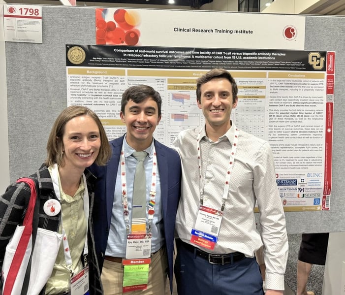 Three researchers smile in front of a poster board of research.