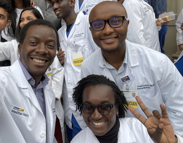 Three doctors wearing their white coats smile for a selfie.