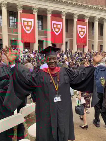 Isaac Acquah smiles while wearing a graduation cap and gown at Harvard University.