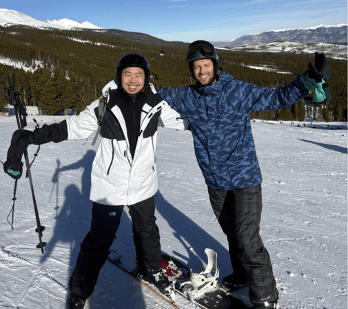 Two people dressed in skiing and snowboarding gear smile on a snowy mountain.