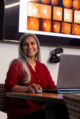 Jayashree Kalpathy-Cramer, PhD, smiles while working on a computer.
