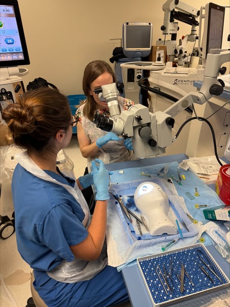 Two women practice an eye procedure on a synthetic eye in a lab.