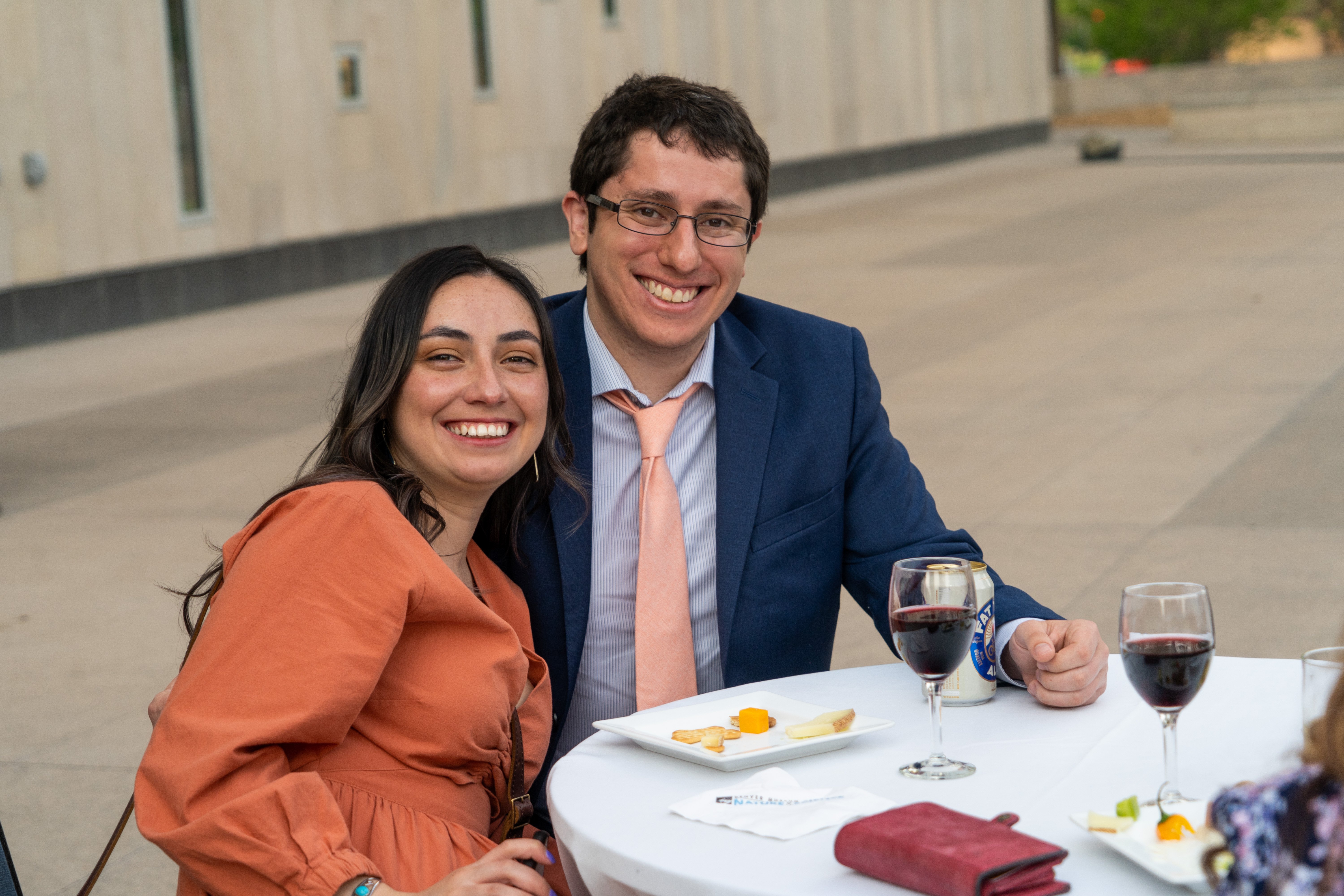 two people dressed nicely sitting at a table outside