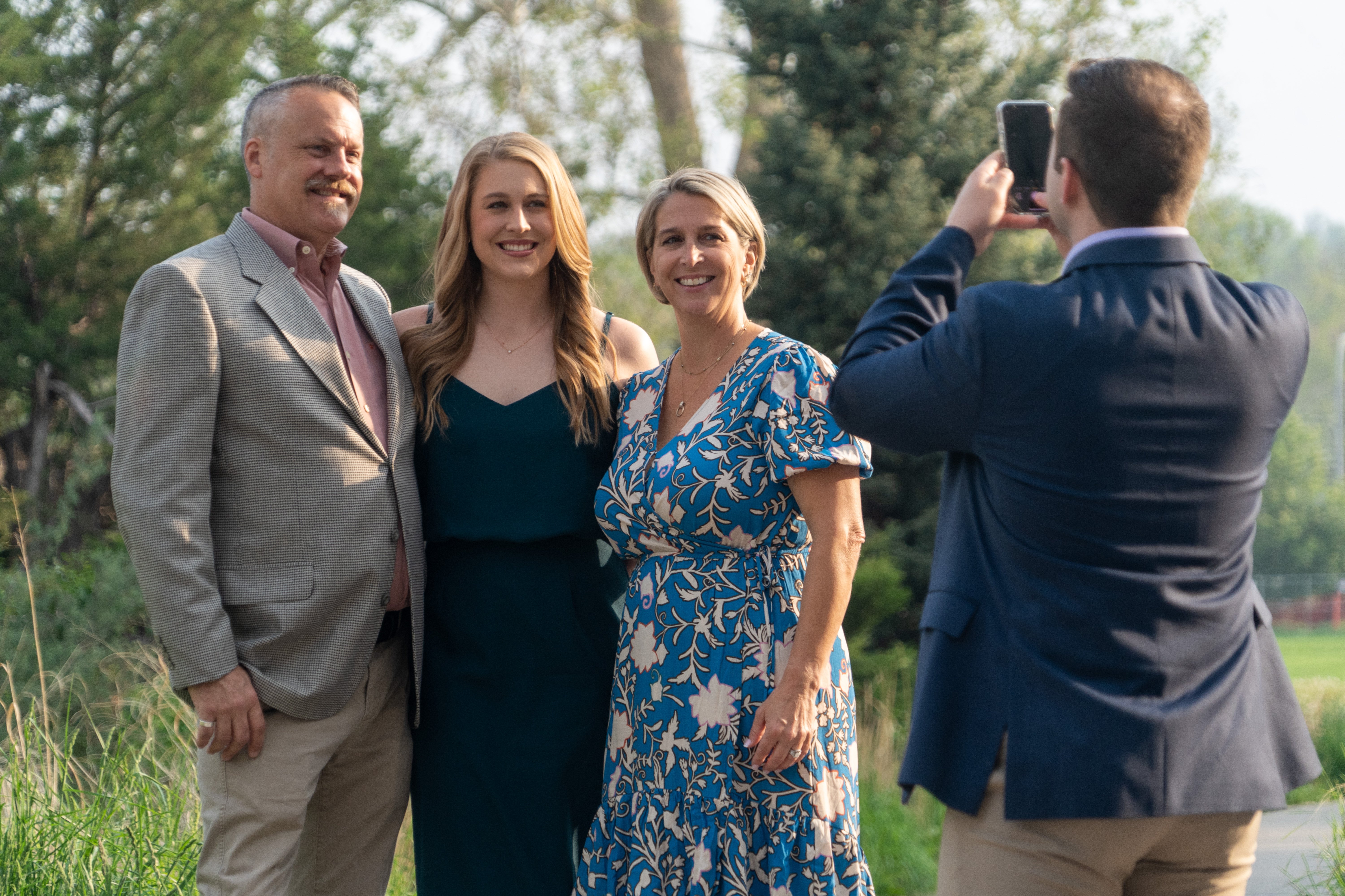 three people standing next to each other having their photo taken by another person on their phone
