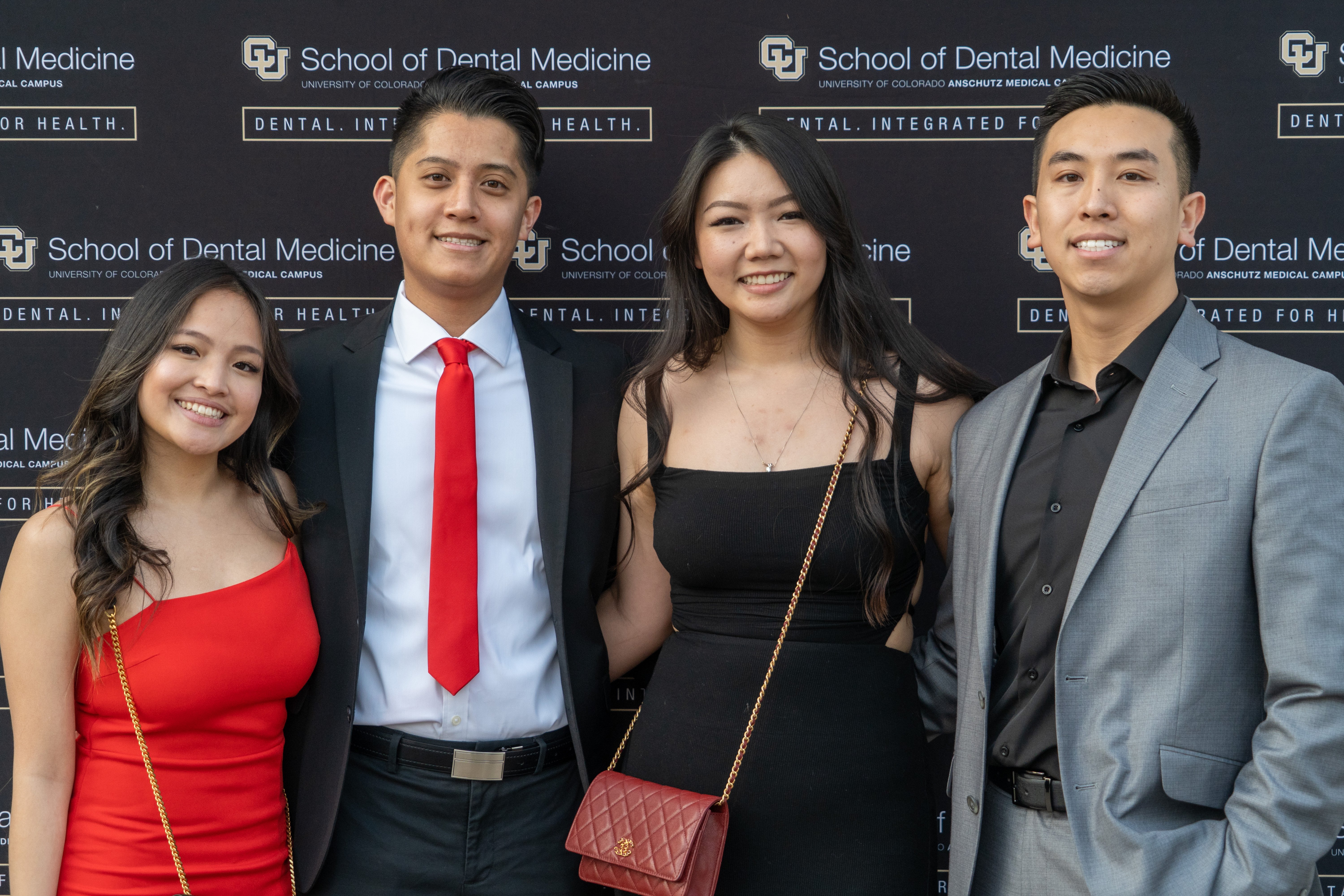 four people standing together in front of a black backdrop