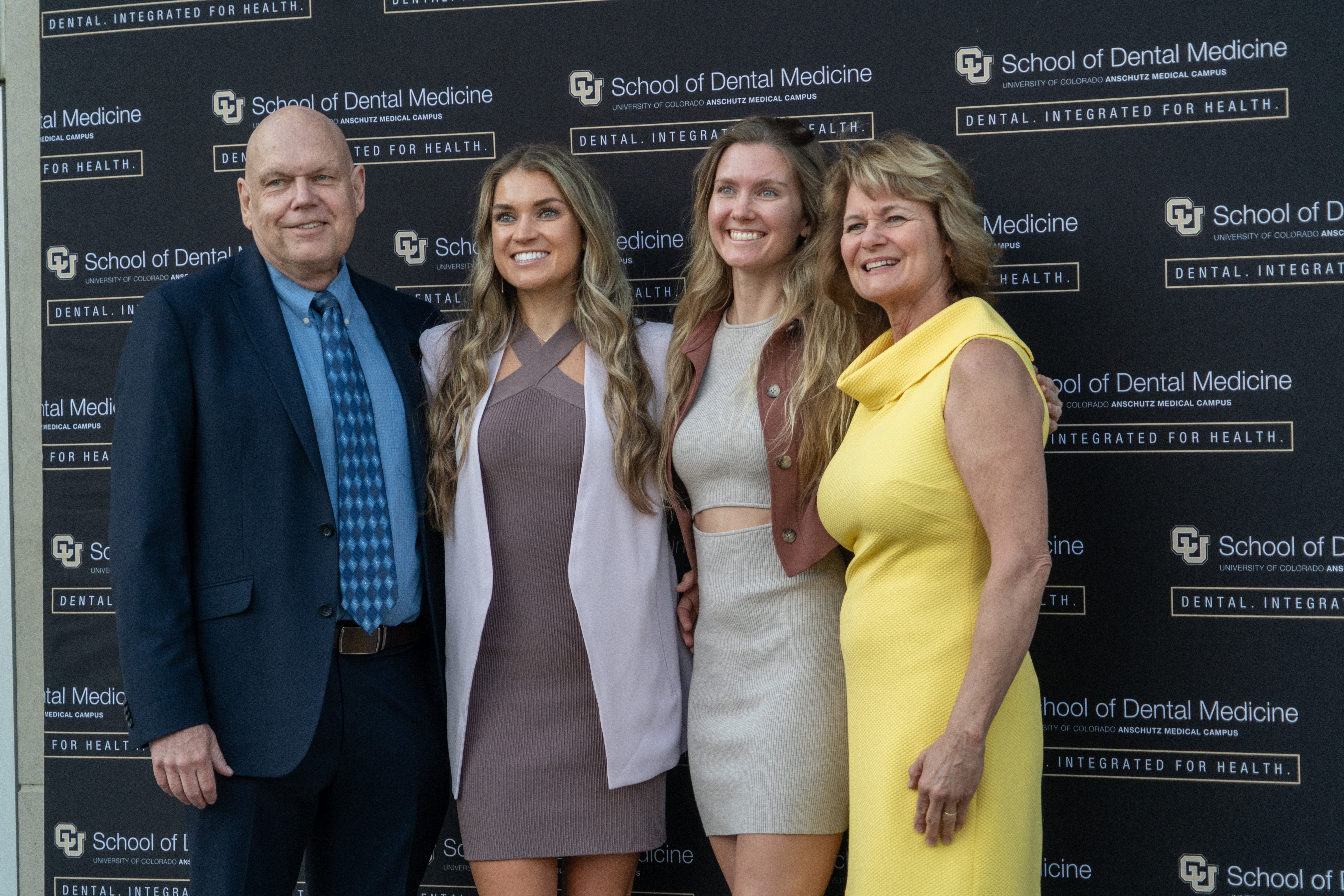 four people standing together in front of a black backdrop
