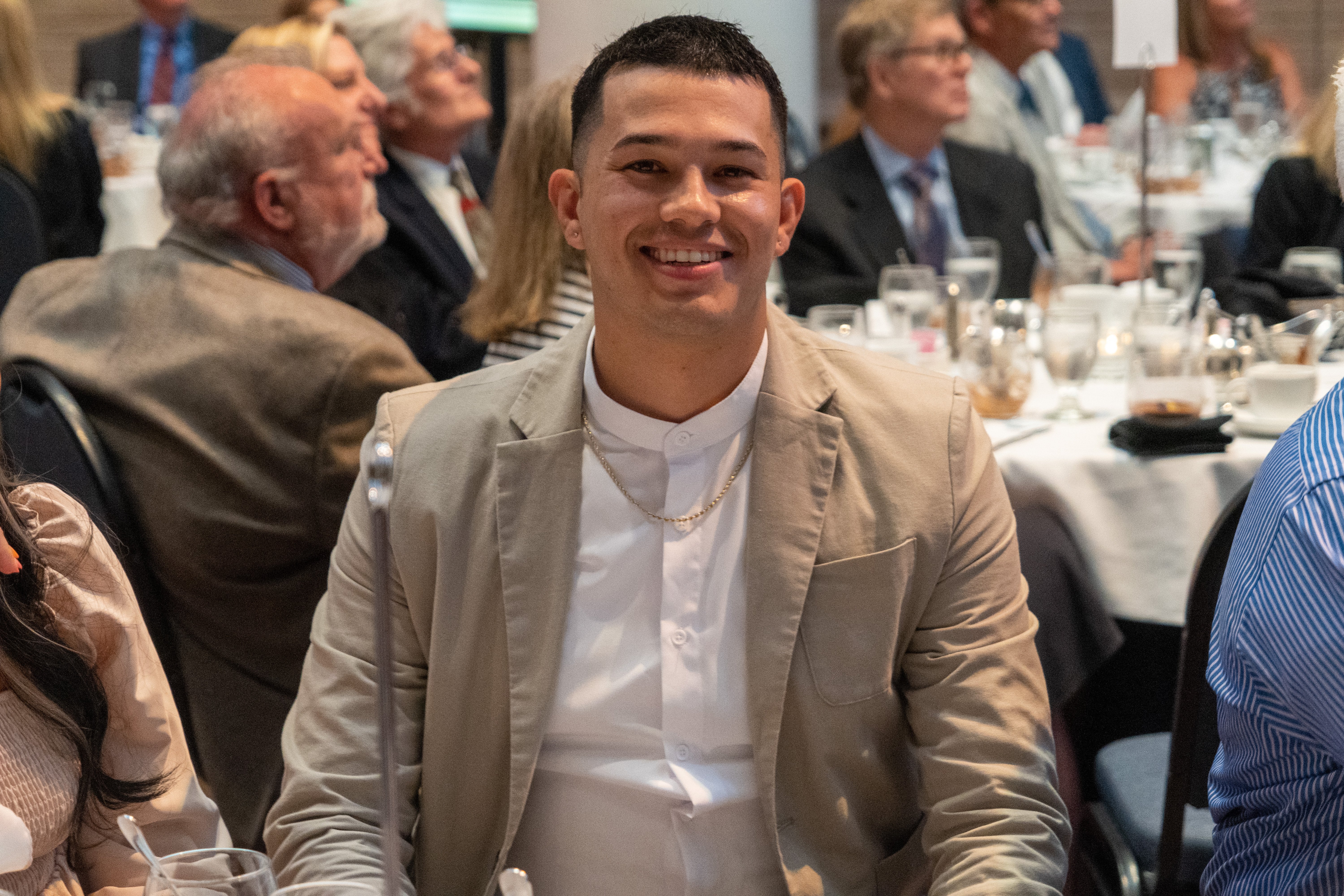 man smiling at the camera while seated at a table inside