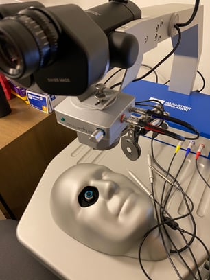 The simulator features a microscope and model head with electronic eyeball.