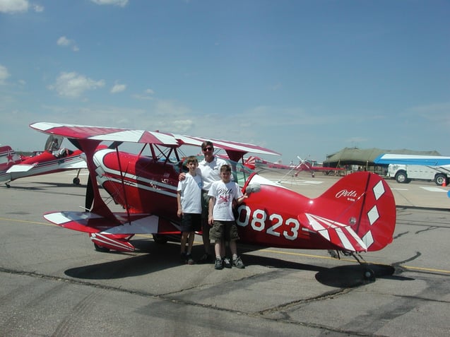 Geoff Slingsby standing with his two children beside a red plane.