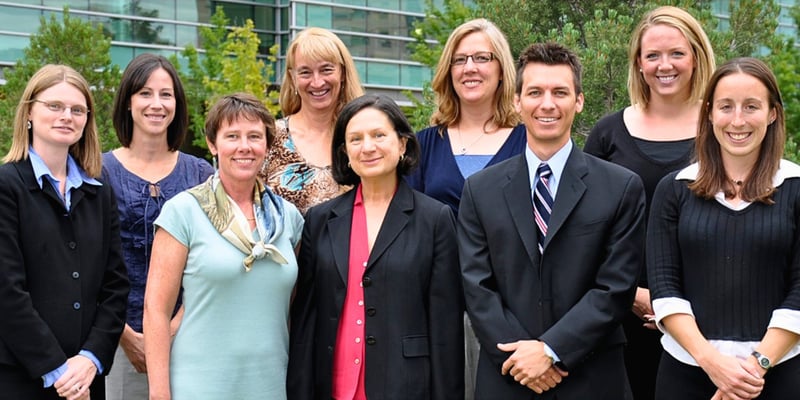 Nine health care workers smile together while standing outside at the CU Anschutz campus.