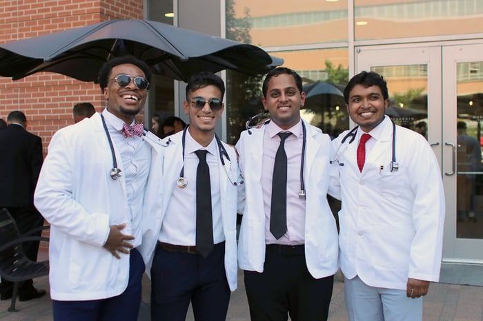Four first-year medical students smiling while wearing their white coats and stethoscopes.