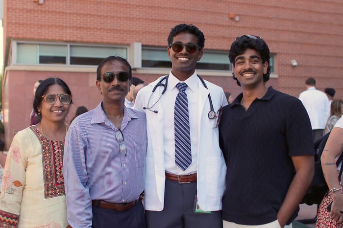 A first-year medical student at CU Anschutz smiles with three loved ones at the Matriculation Ceremony.