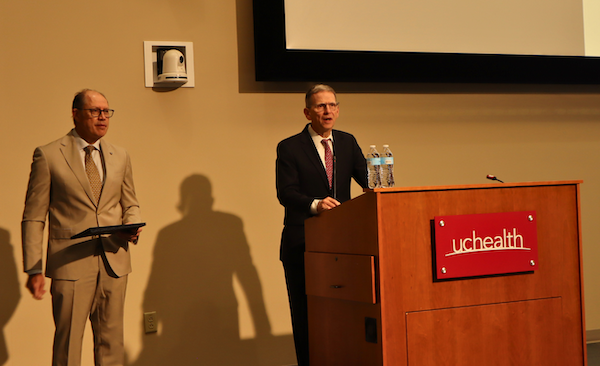 McIntyre stands at a podium with Joseph Cleveland standing to his right