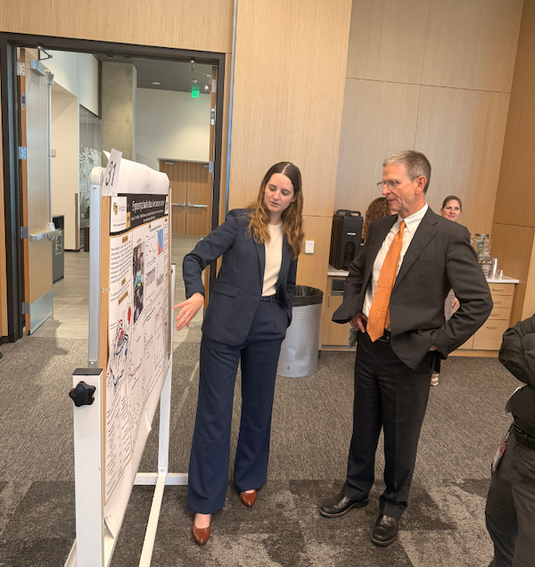 McIntyre listens to Fernanda Pons-Faudoa explaining something on a research poster