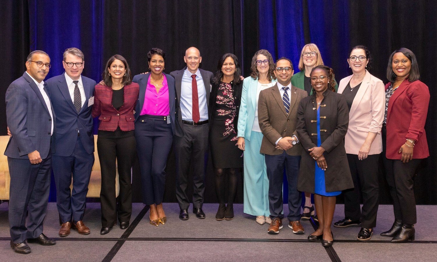 Group of health care professionals smile while standing on stage together.