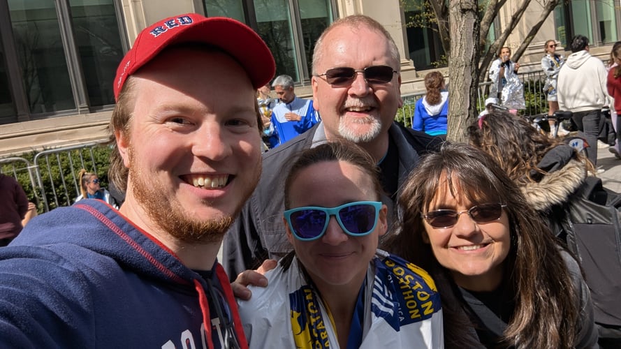 A group photo of four adults smiling together while standing outside.