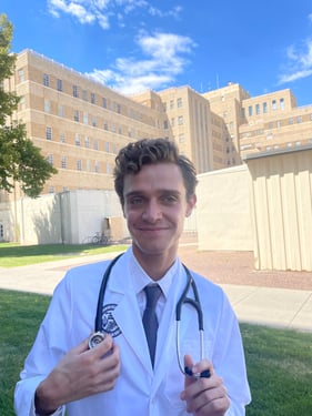 Parker Juels wearing a white coat and stethoscope.