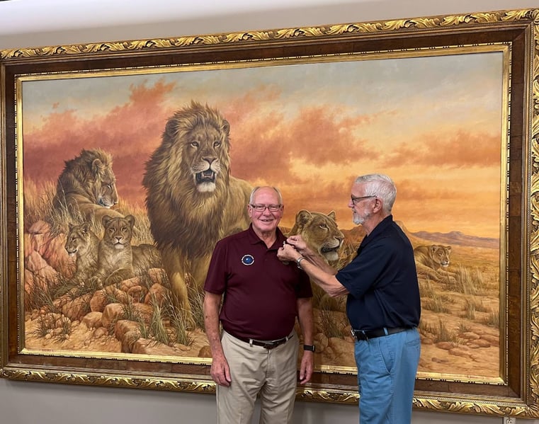 Former International Director Ken Schwols places a pin on John Harper, president of the Rocky Mountain Lions Eye Institute Foundation, in the lobby of the eye institute building in July 2023.