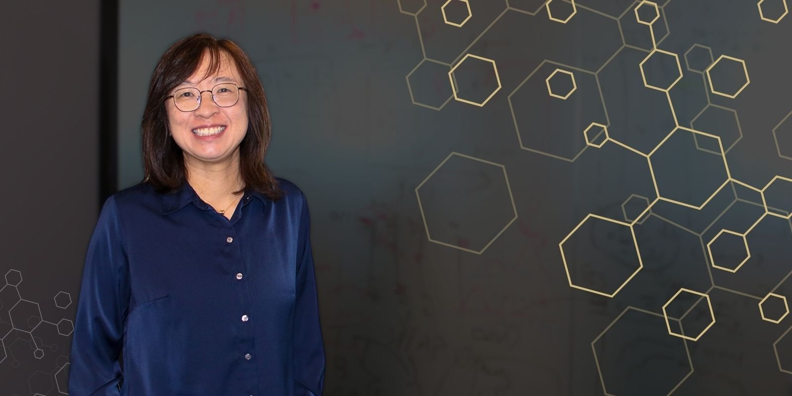 Fan Zhang stands in her office, a hexagon pattern accompanies the photo.
