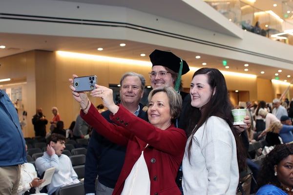 A graduate and their family take a selfie together.