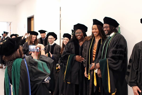 A group of three graduates pose for a picture together.