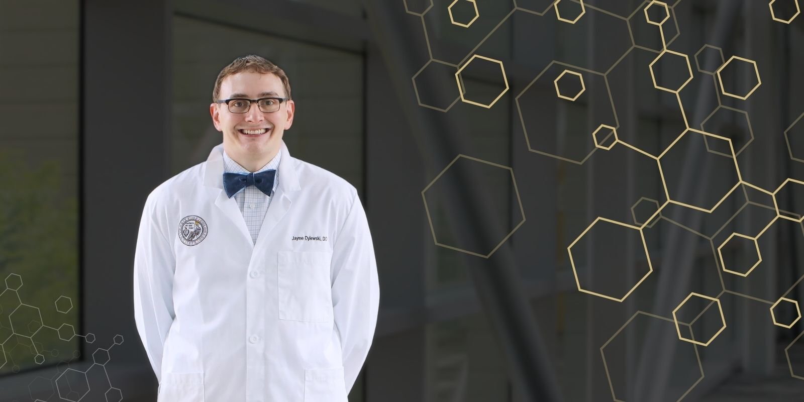 James Dylewski is a white lab coat, gold hexagon pattern.