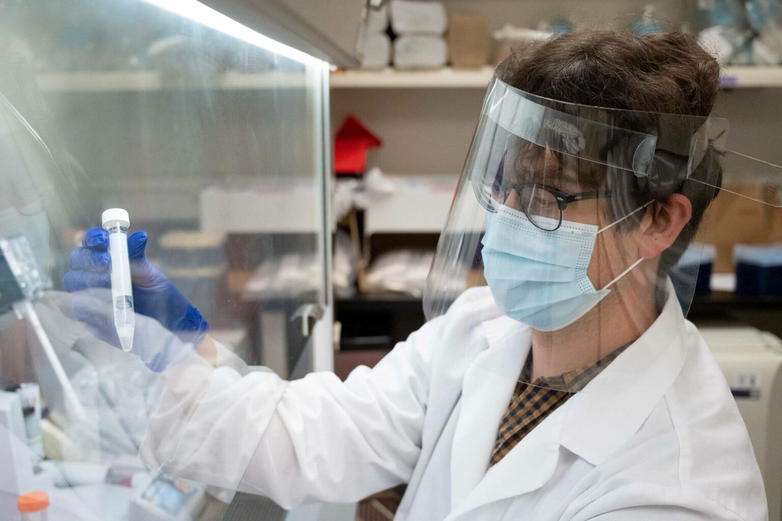 Scientist wearing mask and face shield working under fume hood