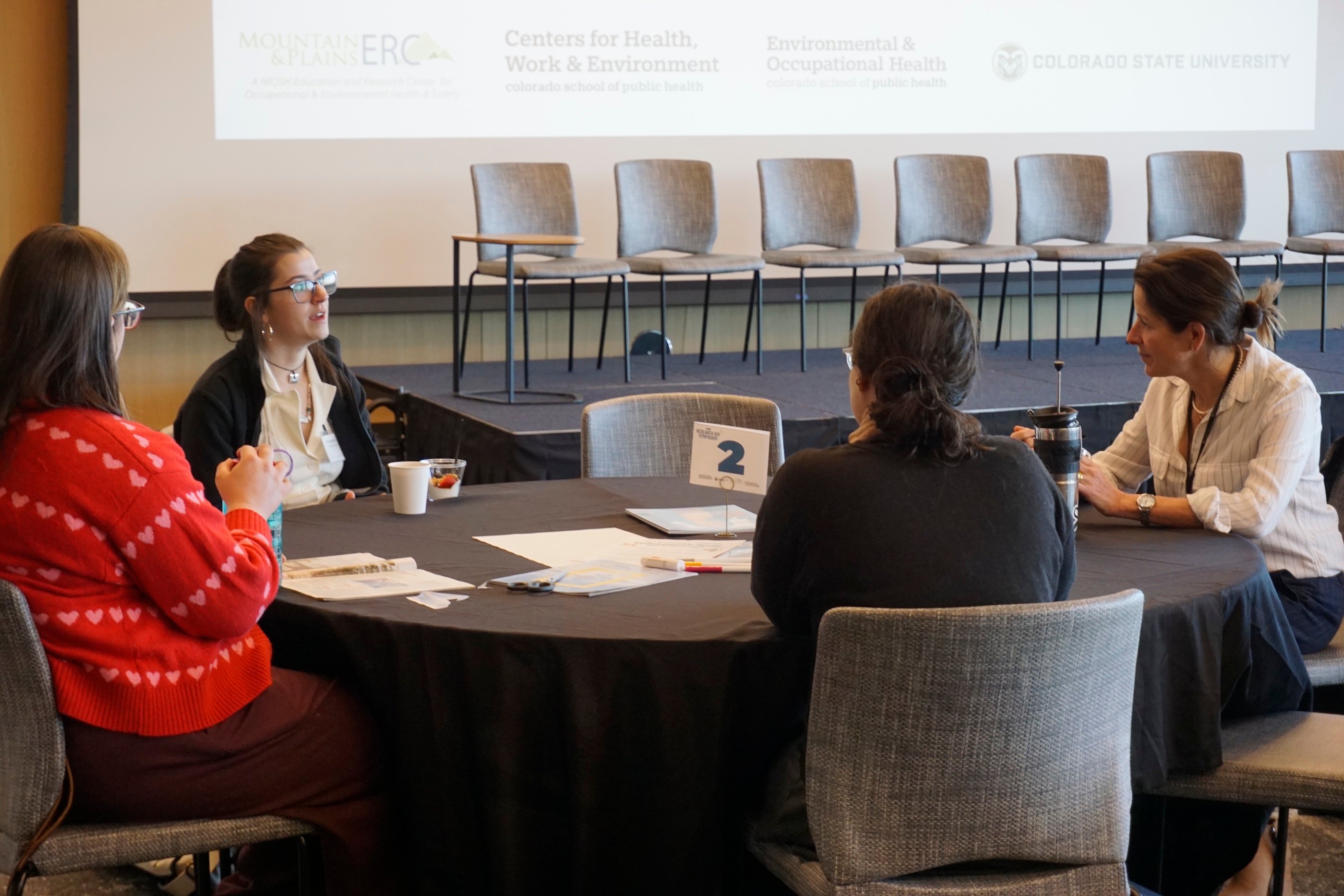 Heather Gilmartin and attendees discussing at a table.