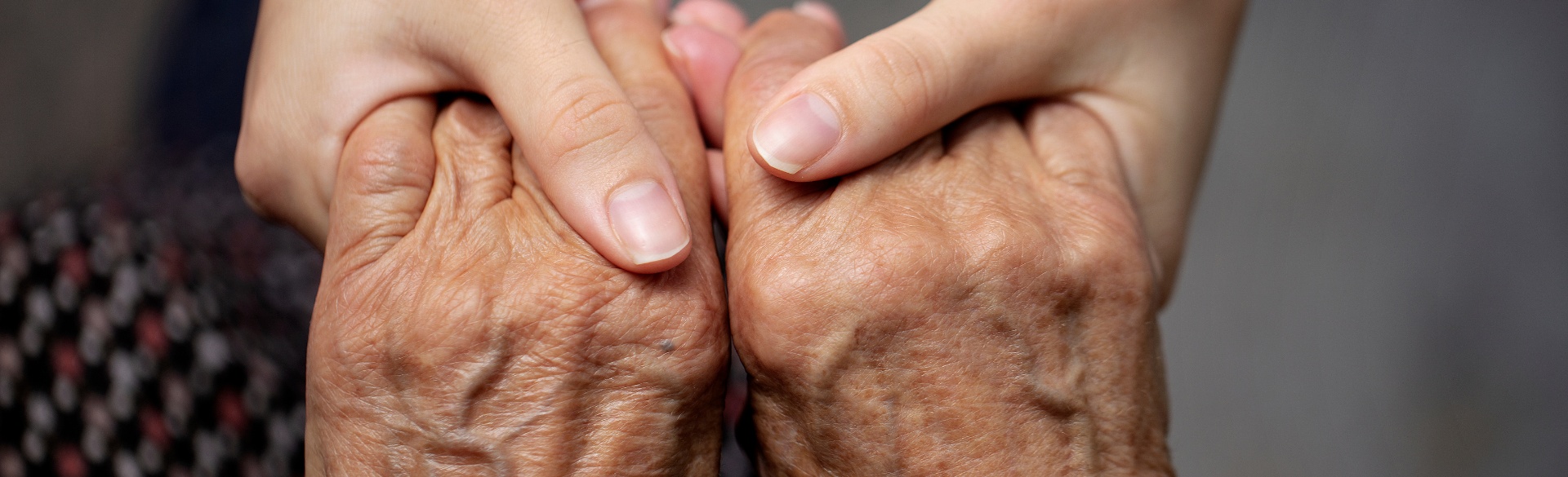 Elderly person holding hands with younger person