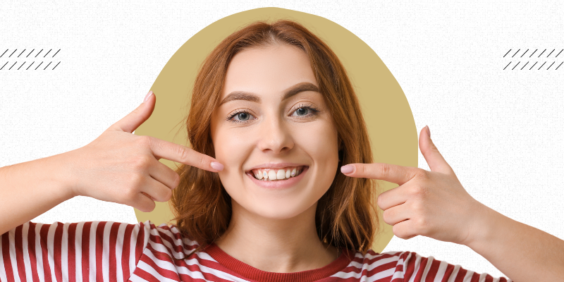 A person smiles with a tooth gem placed on their teeth. 