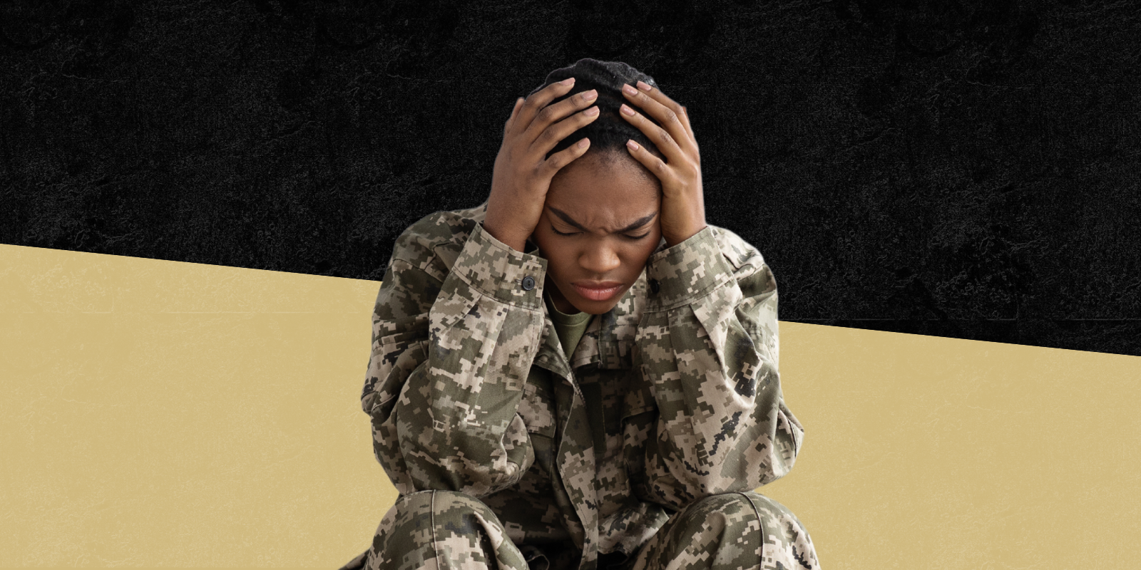 Photo of military individual sitting down with hands on their head 