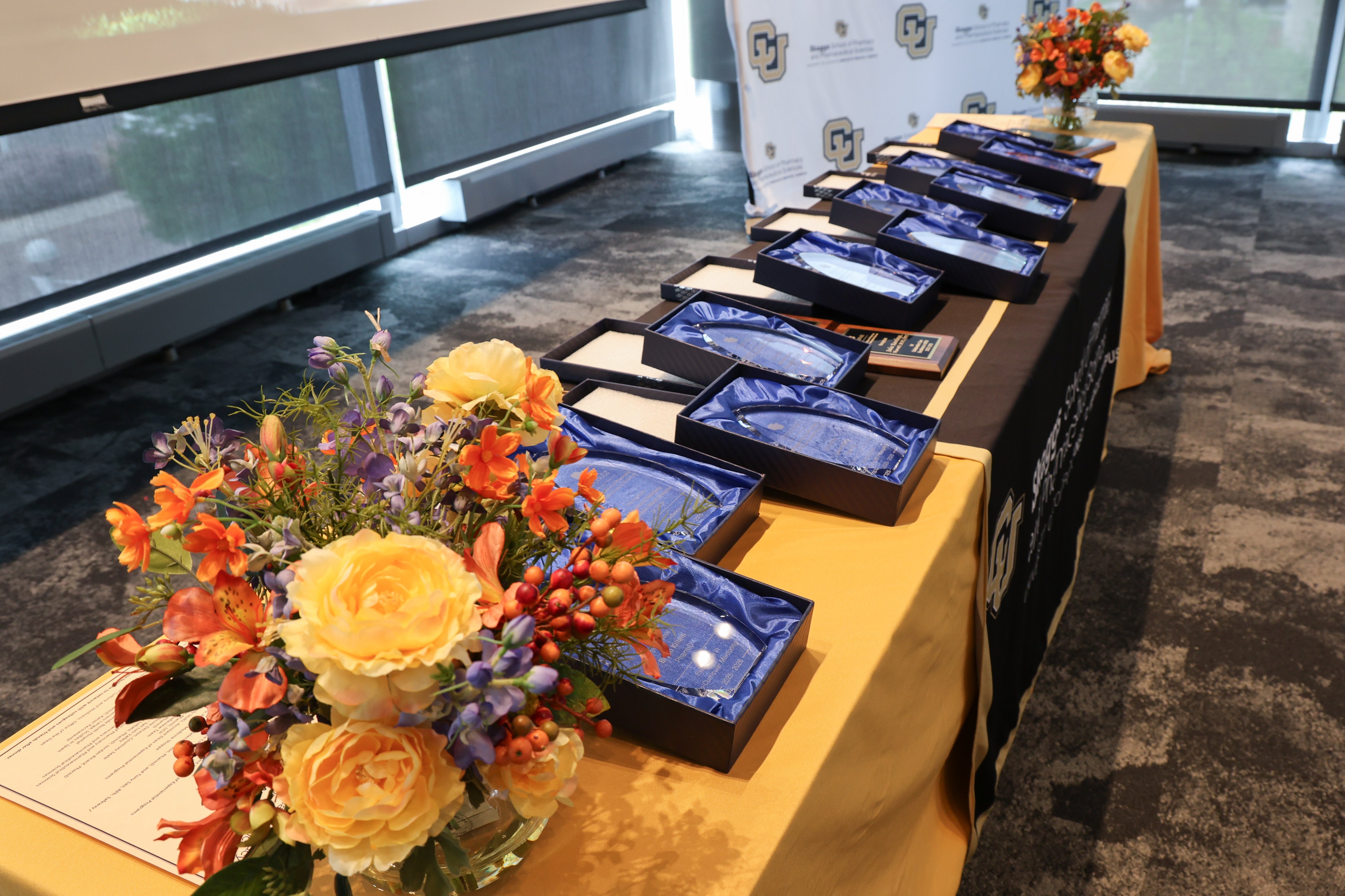 award table with flowers and awards on display in blue satin boxes.