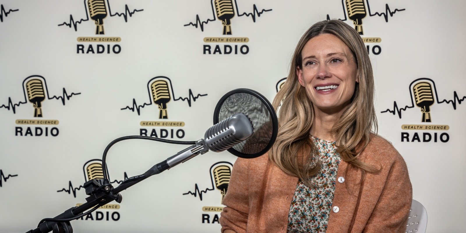 Cristin Welle, PhD, smiling in front of a microphone