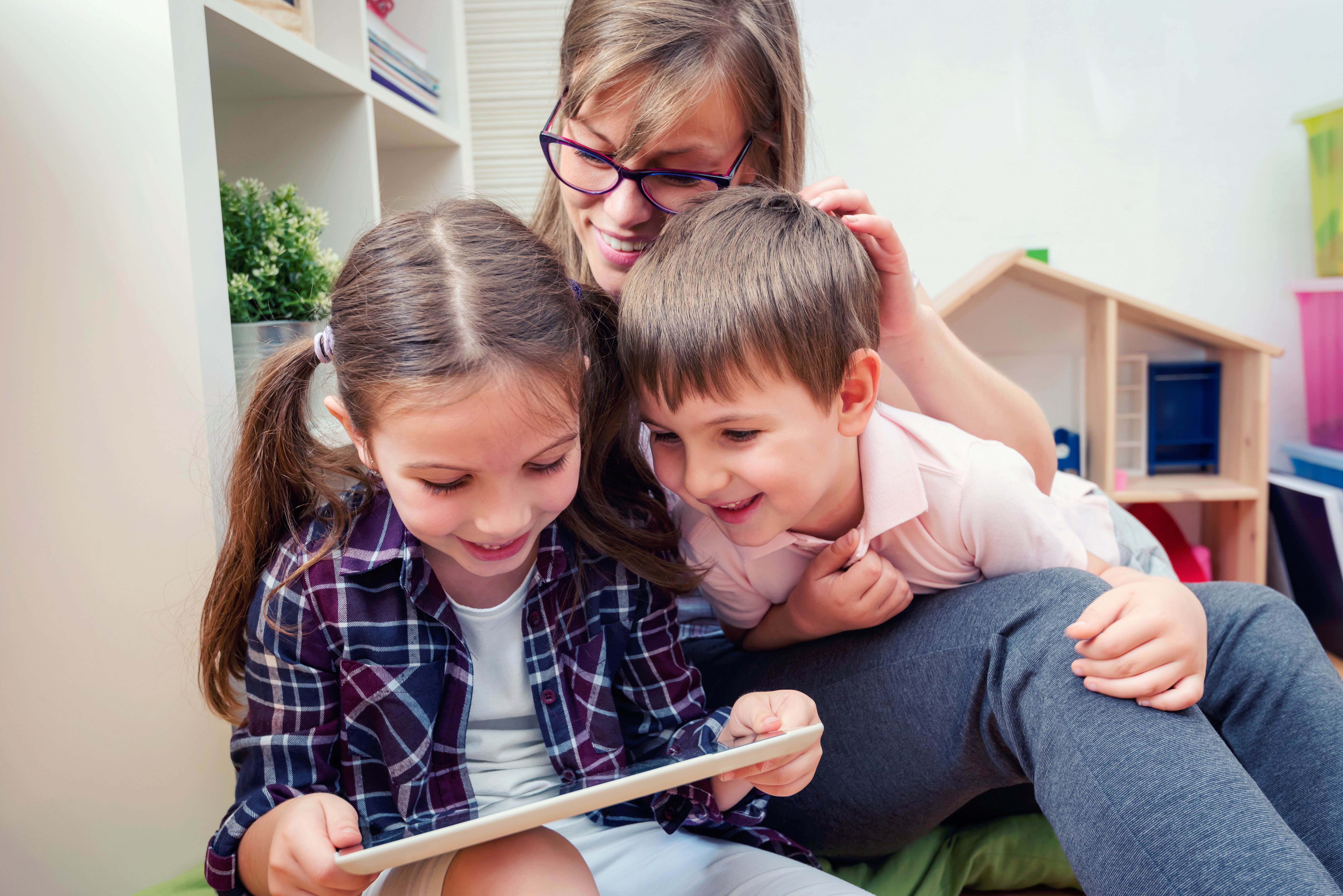 Two kids and their mother look at an ipad screen