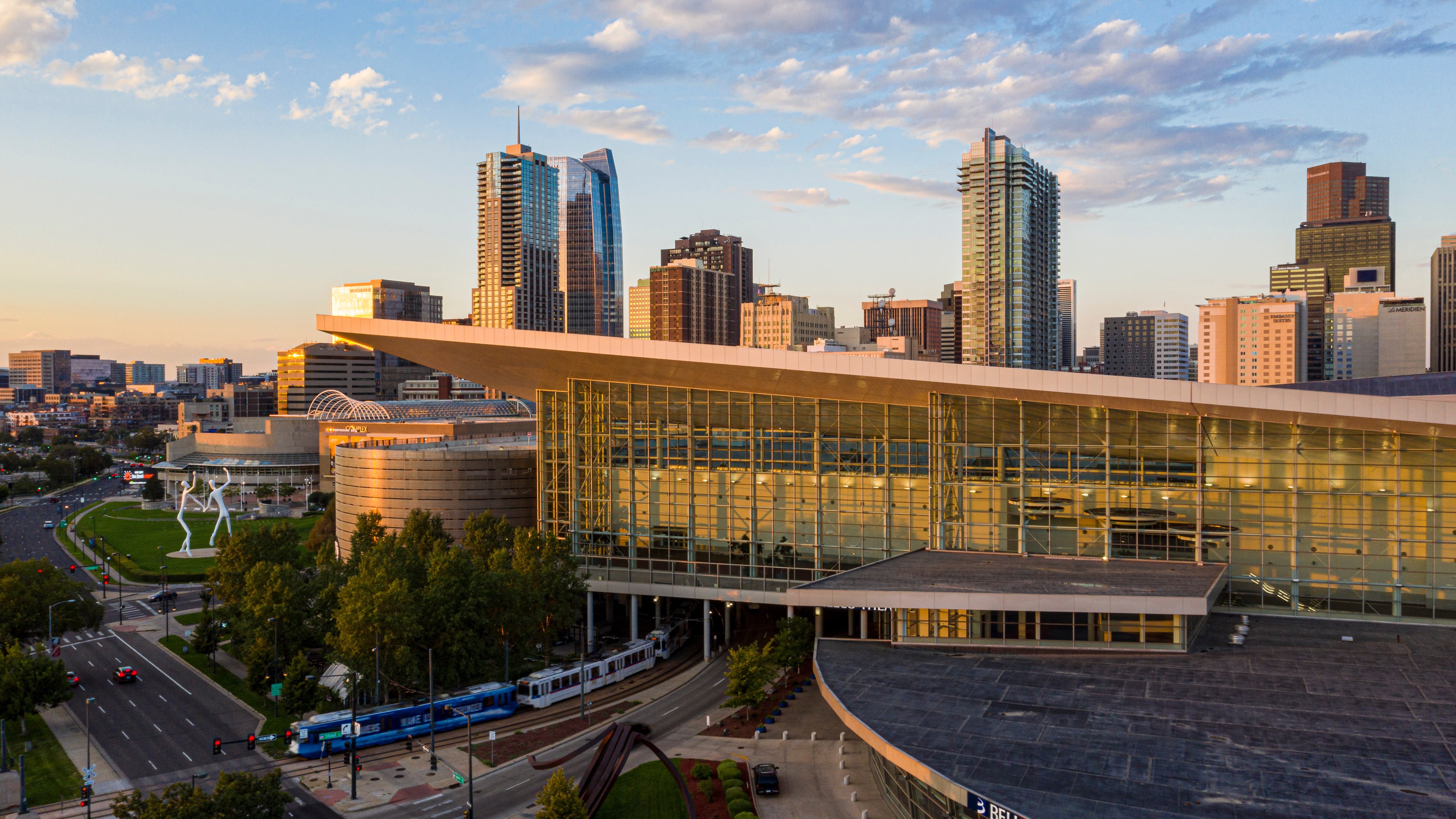 Colorado Convention Center at sunset with the Denver skyline behind the building