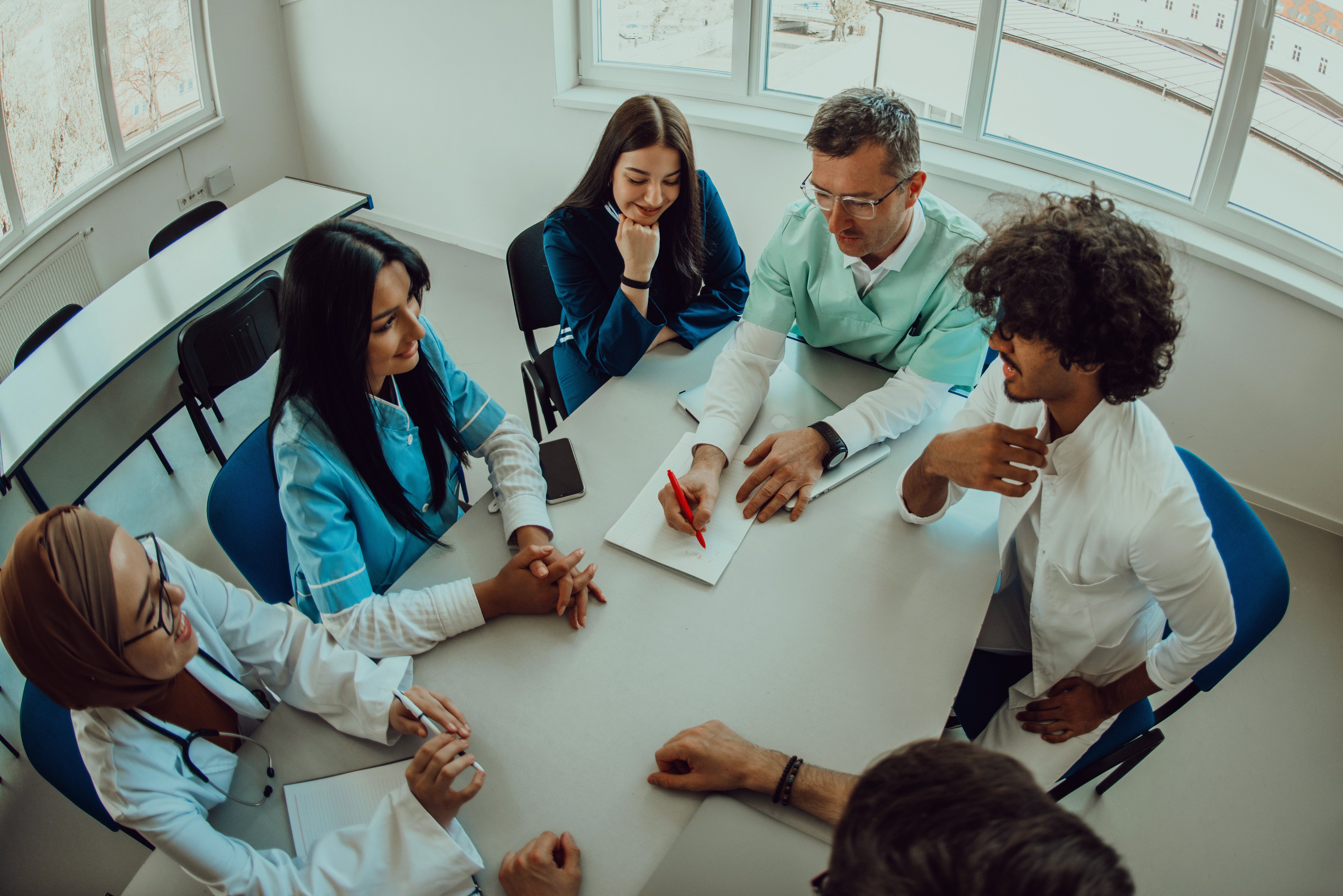 Individuals in the attire of medical providers talking around a table.