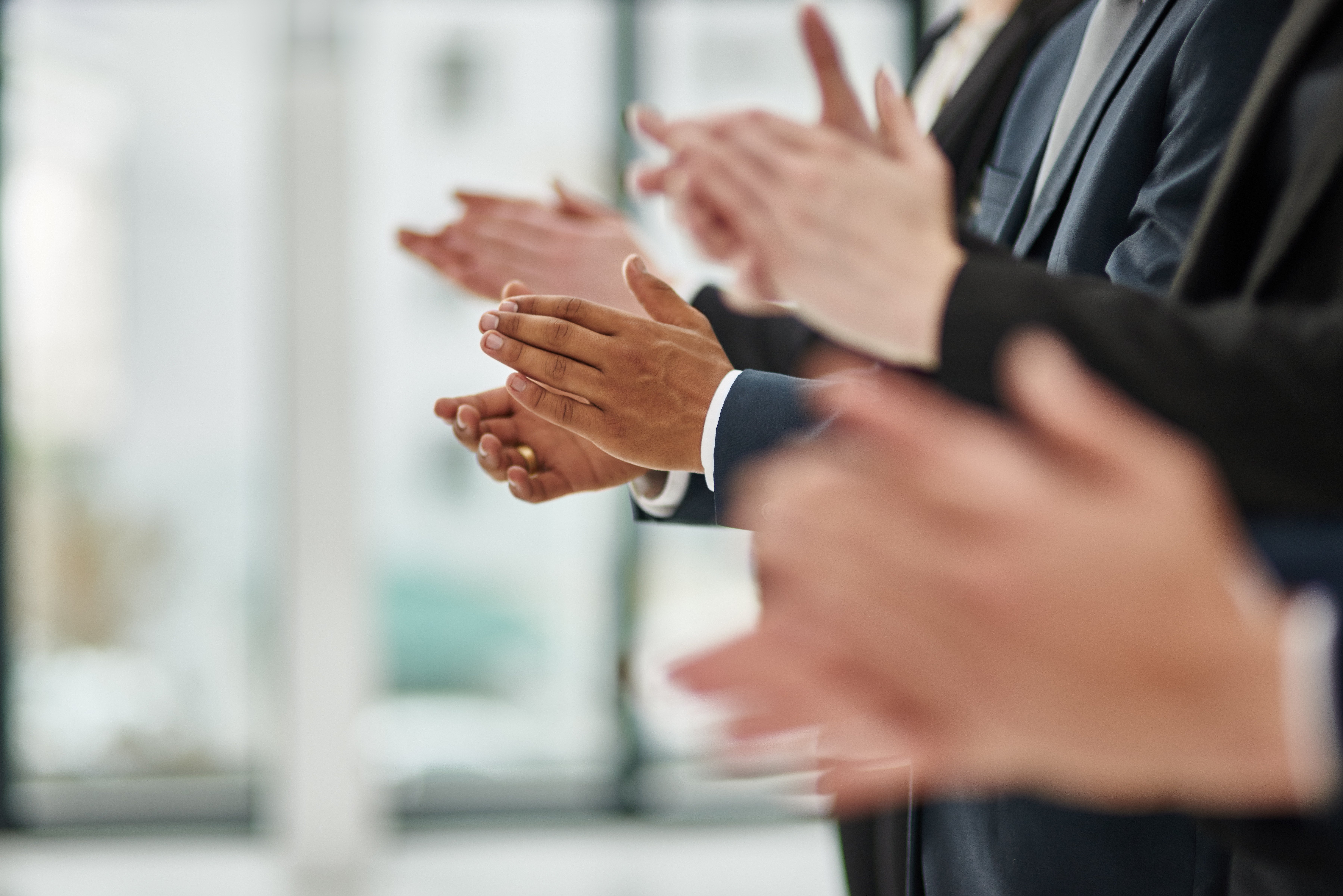 Side view of men in suits clapping