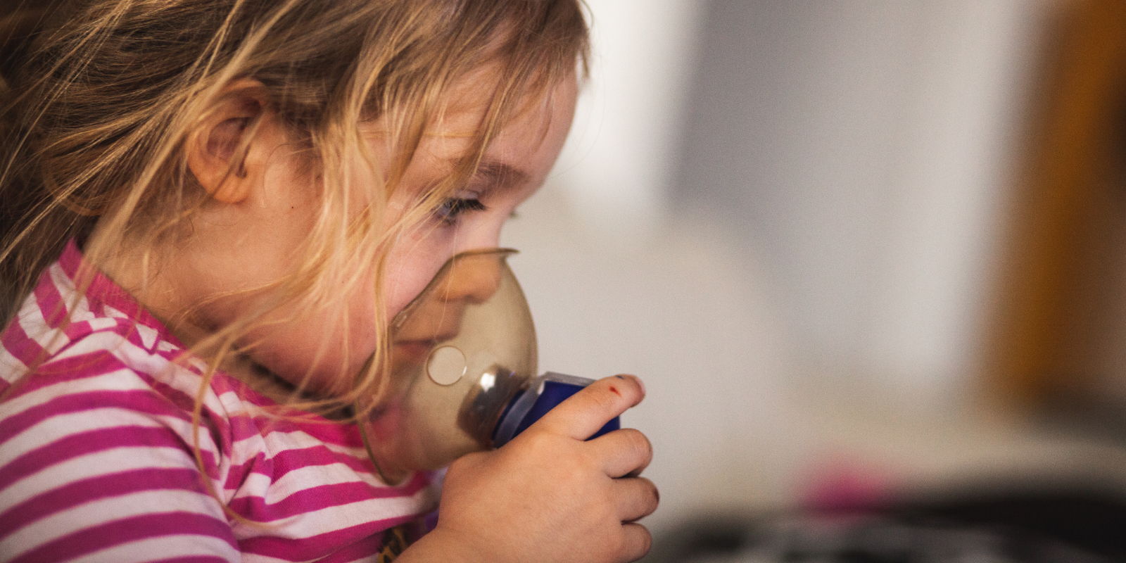 Young girl holding respirator up to face