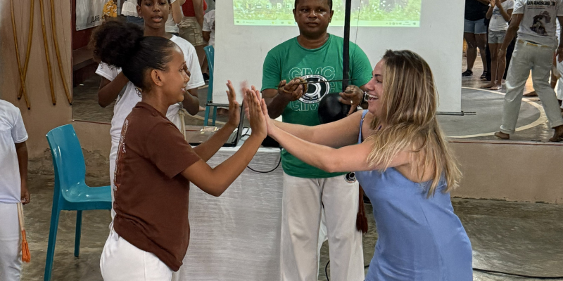 Two women put their hands together in a copeira exercise while two others look on