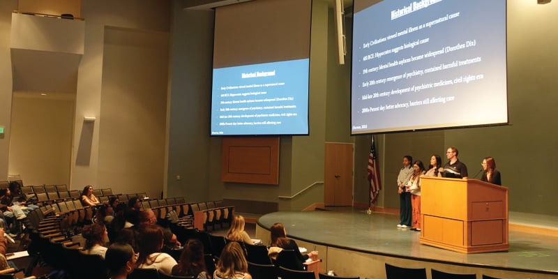 students presenting in front of a crowd