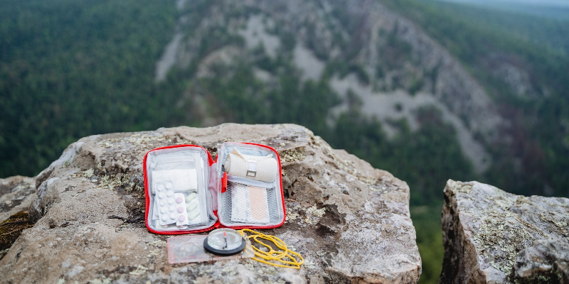 first aid kit sitting atop a rock on a mountain