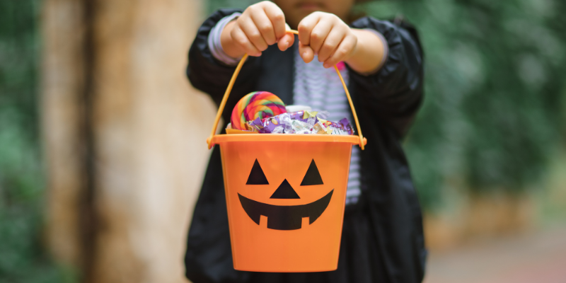 a child holds a halloween bucket of candy