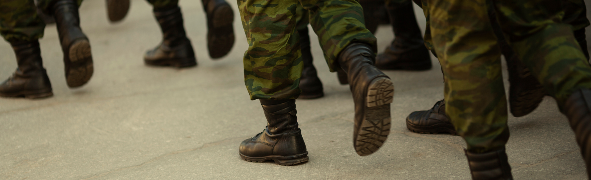 Close-up of military members marching in boots and camouflage